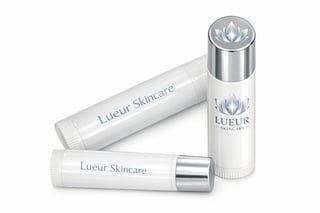 Three white skincare products from Lueur Skincare brand with silver metallic accents and caps arranged on white background